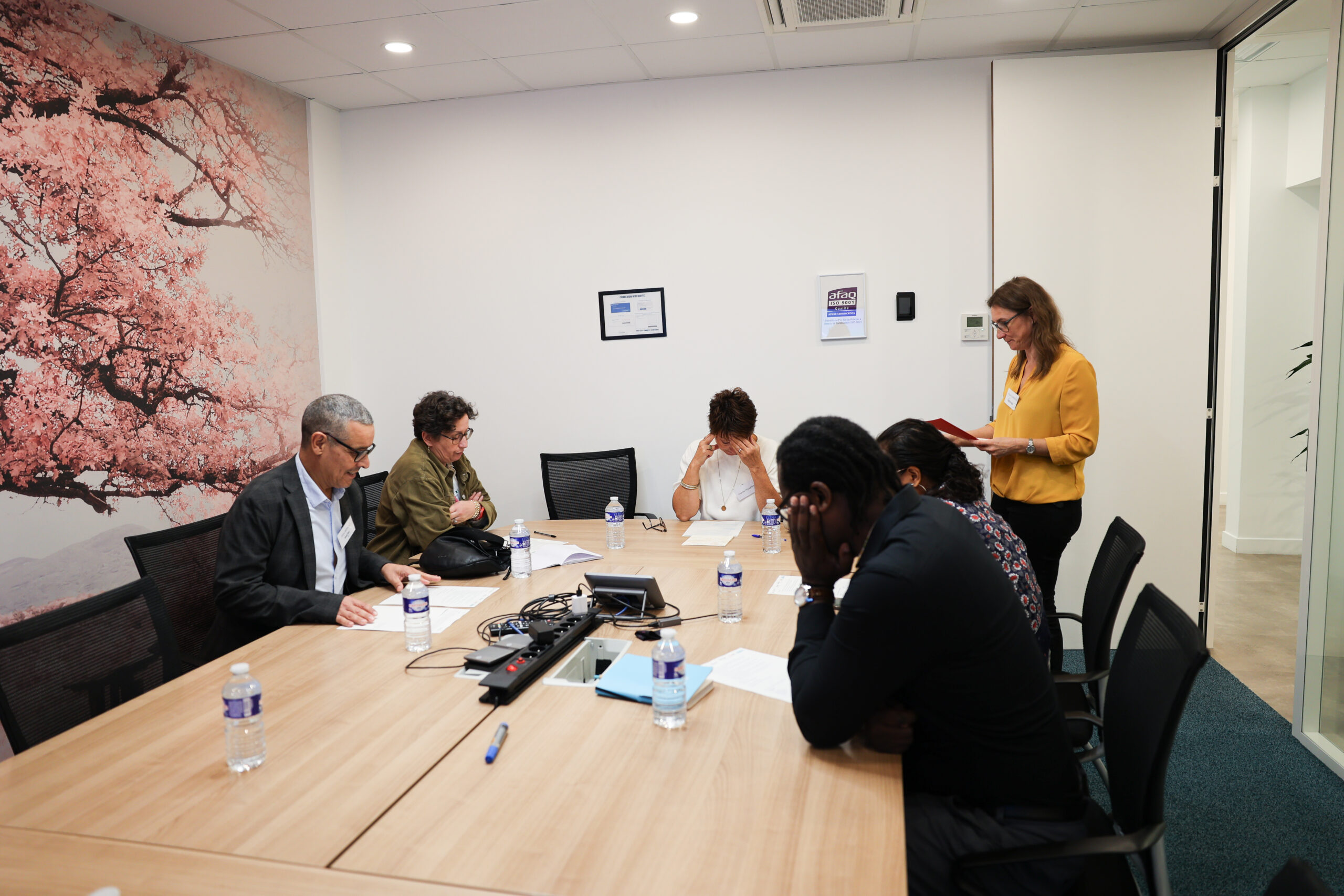 Atelier en sous-groupe : des participants réfléchissent autour d'une table de réunion pendant qu'une animatrice consulte ses notes.